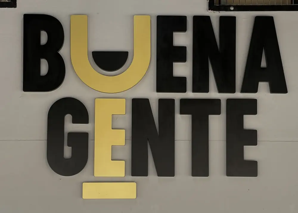 Rótulo corpóreo de Buena Gente en la pared: letras negras con la U y la E en dorado